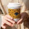 custom printed coffee cup sleeves- image of woman holding takeaway coffee cup with bean printed sleeve design